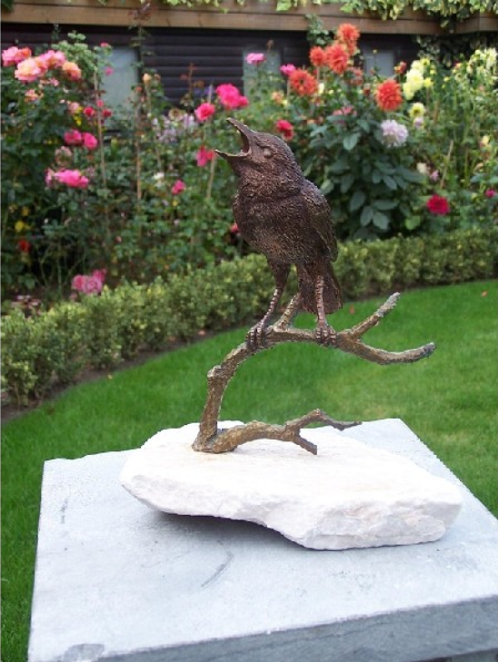 Bronzen beeld vogel op witte steen